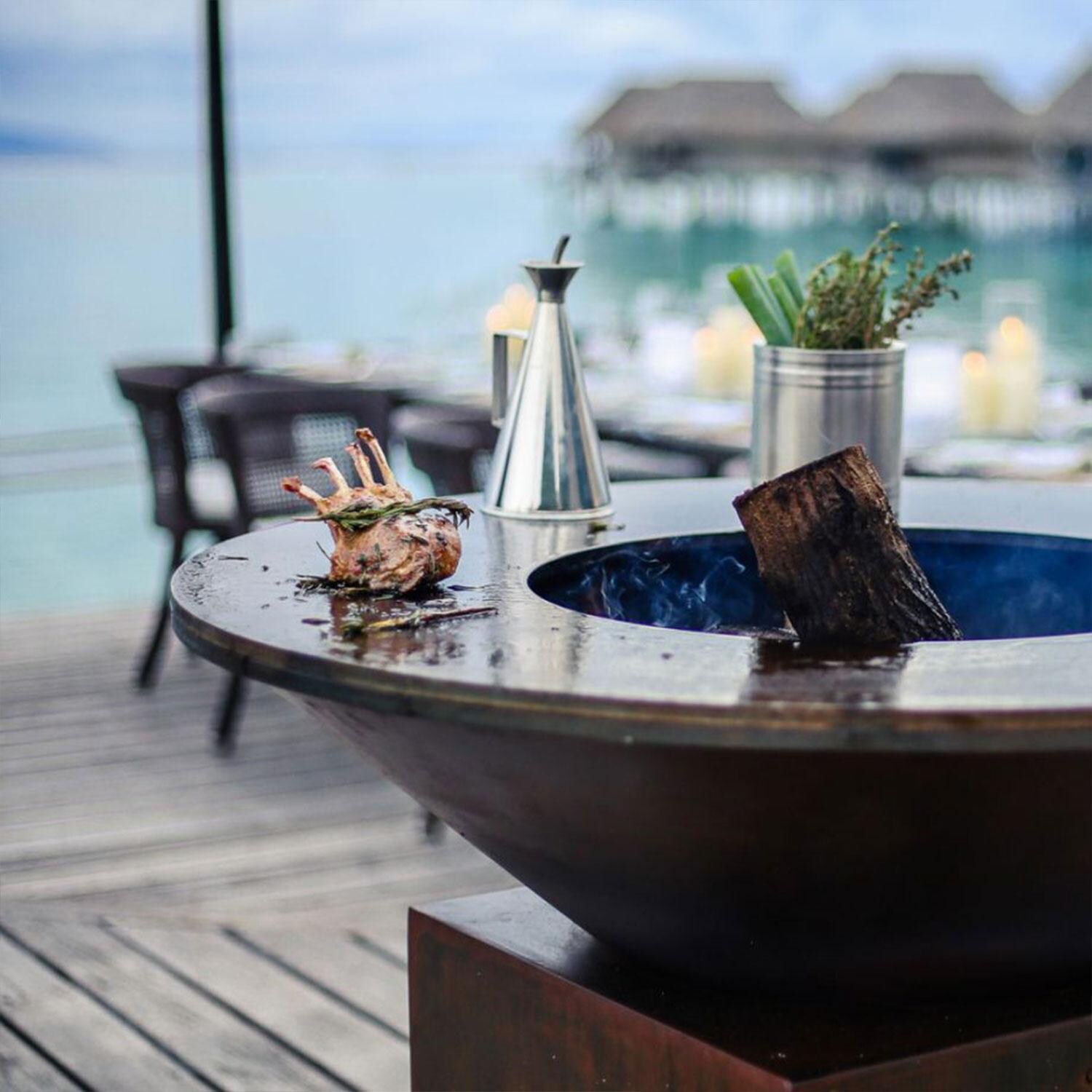 OFYR OCS-85 Classic Storage Corten 85 35 Inch Wood-Fired Flat Top Grill - Food - Close Up View - Beach Background - Lifestyle thumbnail