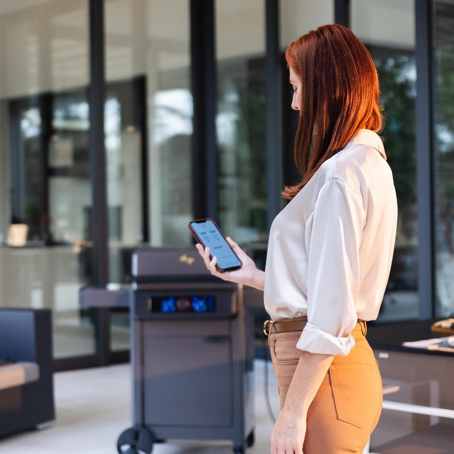 Current 24653014BC Model G Dual Zone Electric Grill W/ Cabinet in Black - Using the App - Lifestyle thumbnail