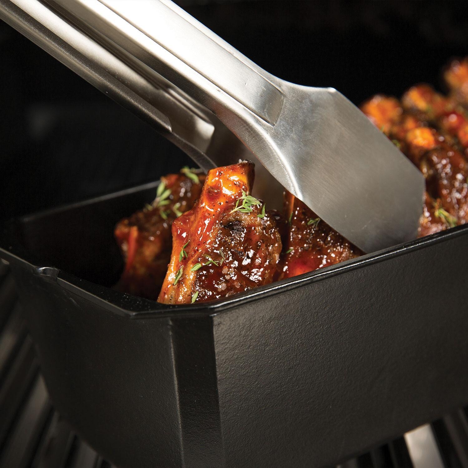 Broil King 69615 Cast Iron Rib Roaster - Using Tongs on Ribs - Up Close - Lifestyle thumbnail