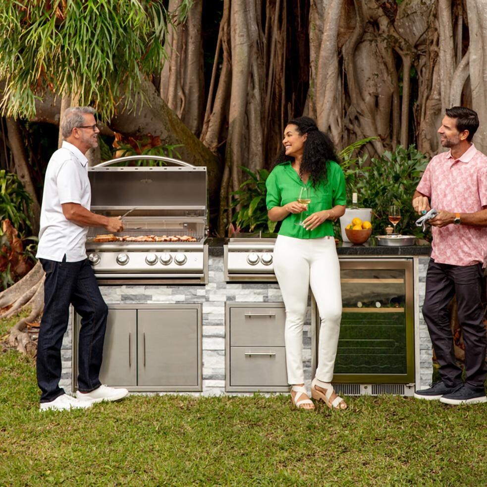 BBQGuys Signature 8 Ft Outdoor Kitchen Island w/ Blaze Premium LTE+ 32-Inch Natural Gas Grill, Premium LTE+ Power Burner, 24-Inch Beverage Cooler - Alaska Gray Stone w/ American Black Polished Granite - Gathered Around Island - Lifestyle thumbnail