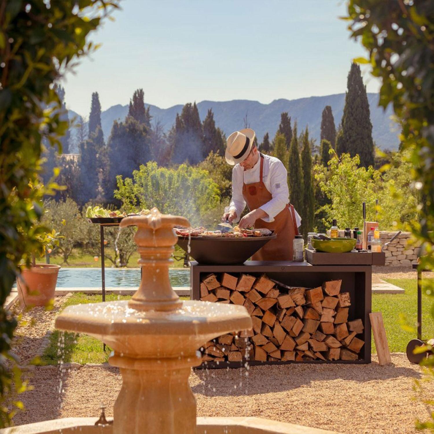 OFYR OIB-85-CD Island Black 85 Ceramic Dark Grey 35 Inch Wood-Fired Flat Top Grill - Grilling By Water Fountain - Lifestyle thumbnail