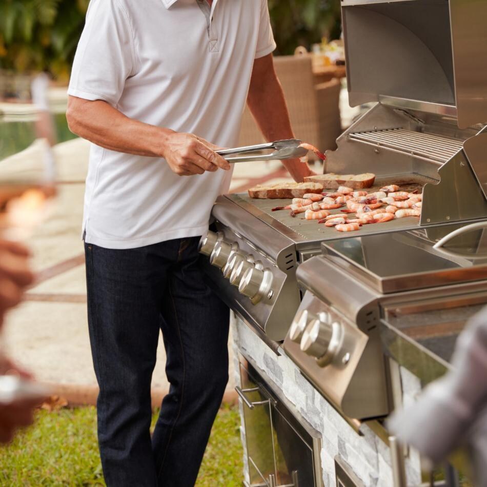 Blaze BLZ-4LTE3MG-LP Premium LTE + Marine Grade 32-Inch 4-Burner Propane Grill With Rear Infrared Burner & Lift-Assist Hood - Man Cooking Angled View - Lifestyle thumbnail