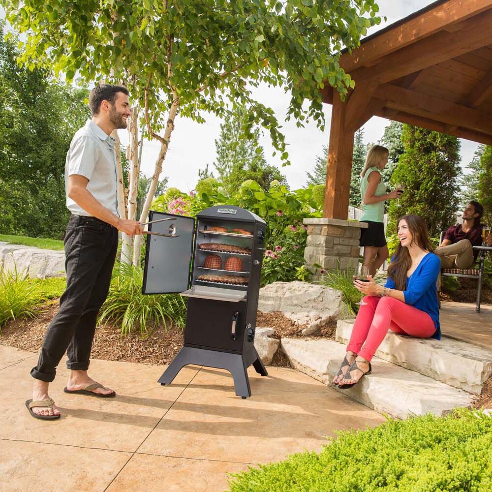 Broil King 28-Inch Smoke Vertical Charcoal Smoker - Black - On Patio with Family - Lifestyle thumbnail