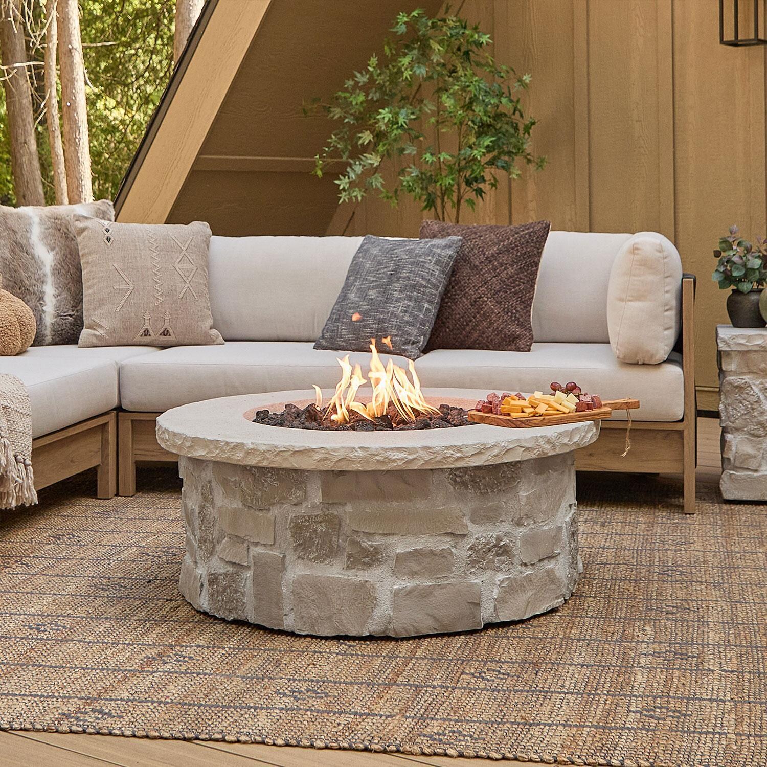 Heritage 40 Inch Round Stone Propane Fire Pit Table in Beige by Lakeview Outdoor Designs - W/ Sectional (Sold Separately) - Lifestyle thumbnail