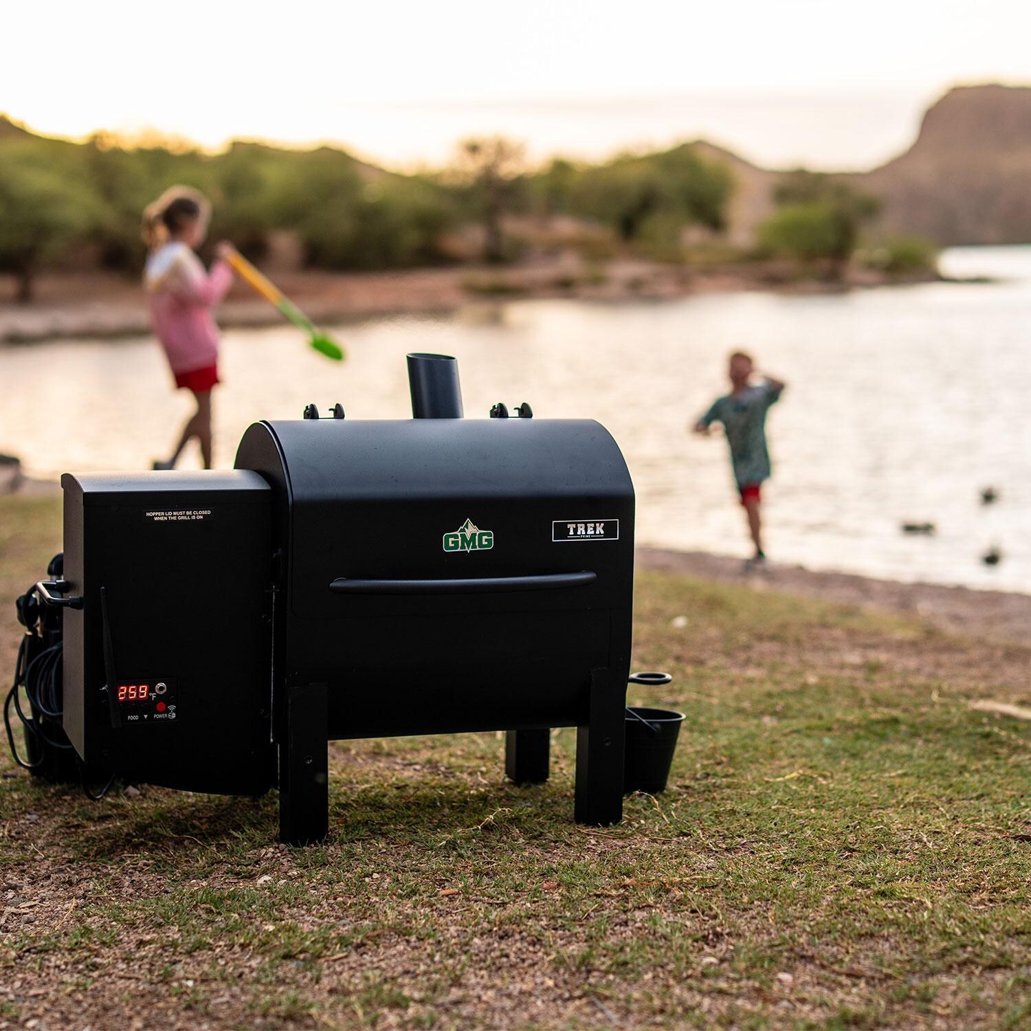 Green Mountain Grills Trek Prime 2.0 WiFi Pellet Grill w/ Cover - Kids Playing in Background - Lifestyle thumbnail