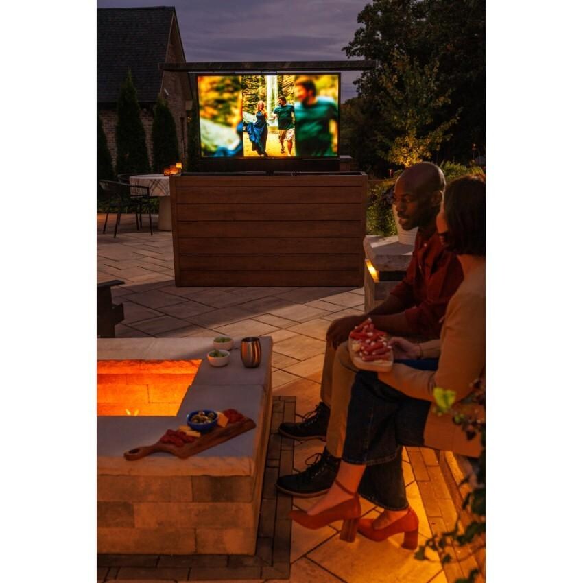 BBQGuys Signature 72 Inch 360 Degree Swivel Outdoor TV Lift Cabinet | Toffee w/ Black Granite - Enjoying TV by Firepit - Lifestyle thumbnail