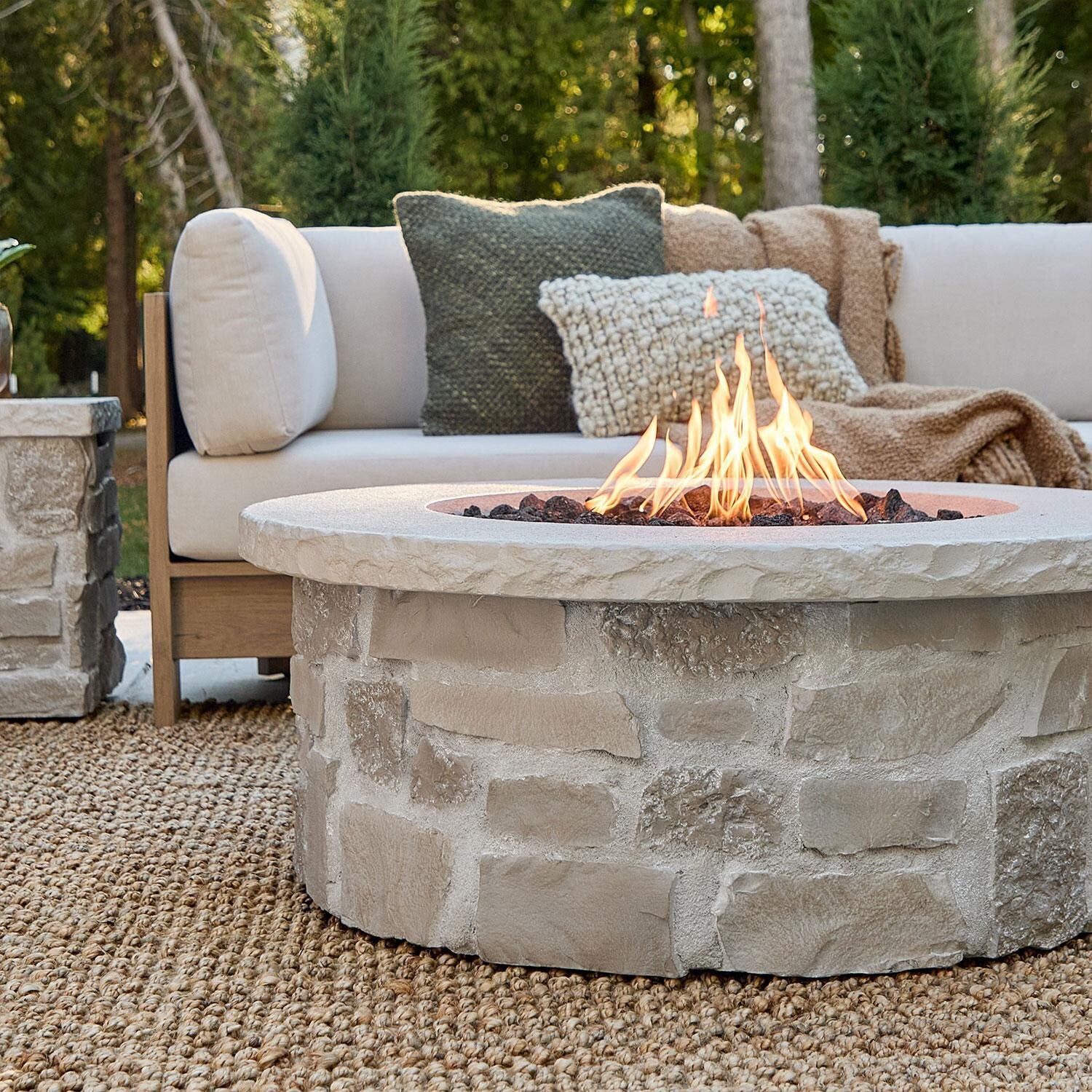 Heritage 40 Inch Round Stone Propane Fire Pit Table in Beige by Lakeview Outdoor Designs - W/ Sectional (Sold Separately) - Close Up - Lifestyle thumbnail