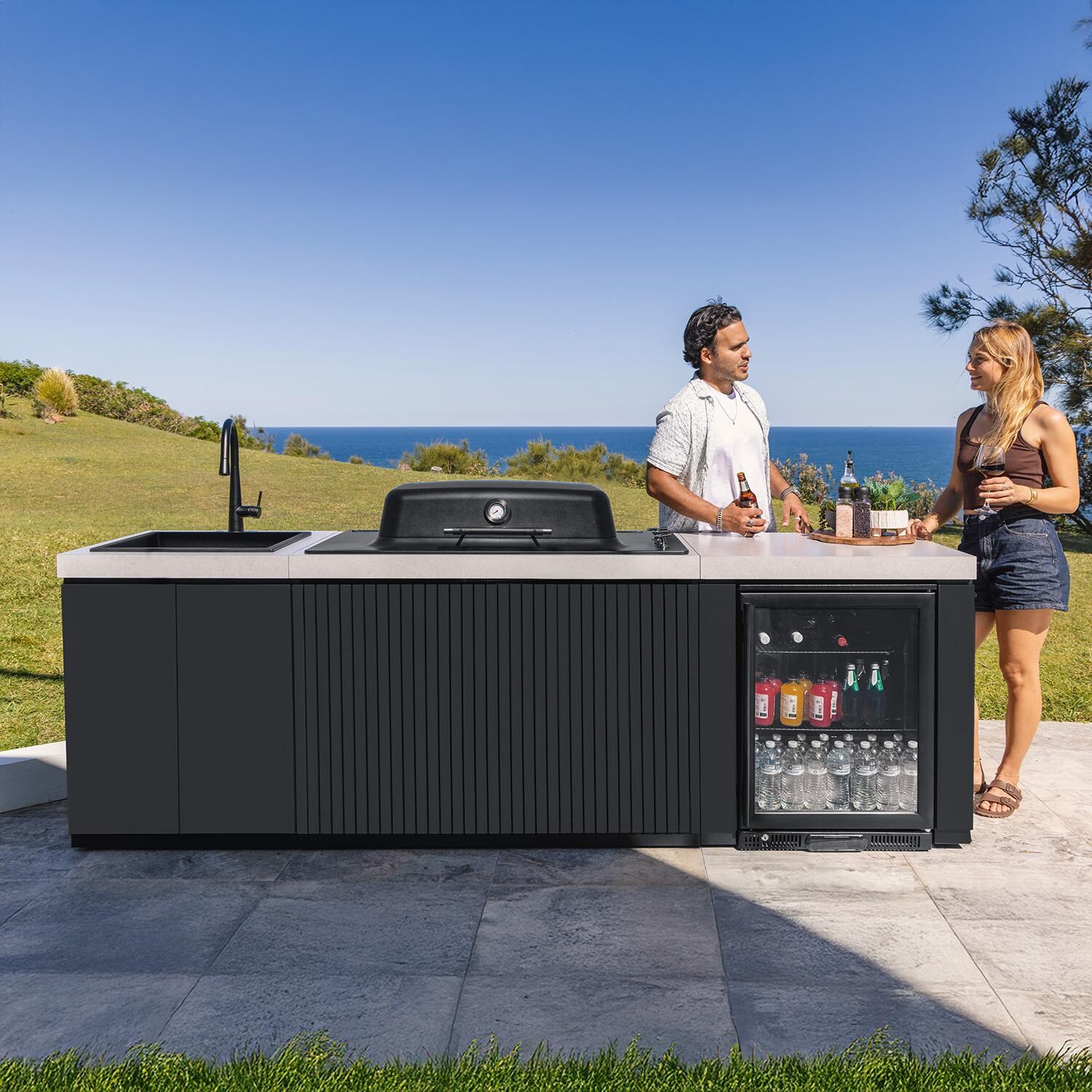 Everdure 9 Ft Outdoor Kitchen Island w/ Marine Grade Aluminum Cabinets in Black - On Patio w/ People - Lifestyle thumbnail