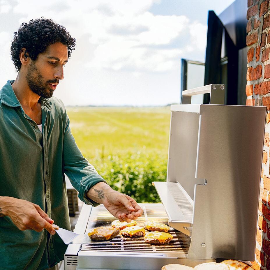 Burnout BBQ Modular Front-Lit Outdoor Kitchen Island w/ Flammkraft Model D Built-In Grill, Caso 4.4 Cu Ft. Refrigreator, Double Drawers, Propane Pullout, and Pullout Waste Bins- Cooking Burgers (Shown in Oak) - Lifestyle thumbnail