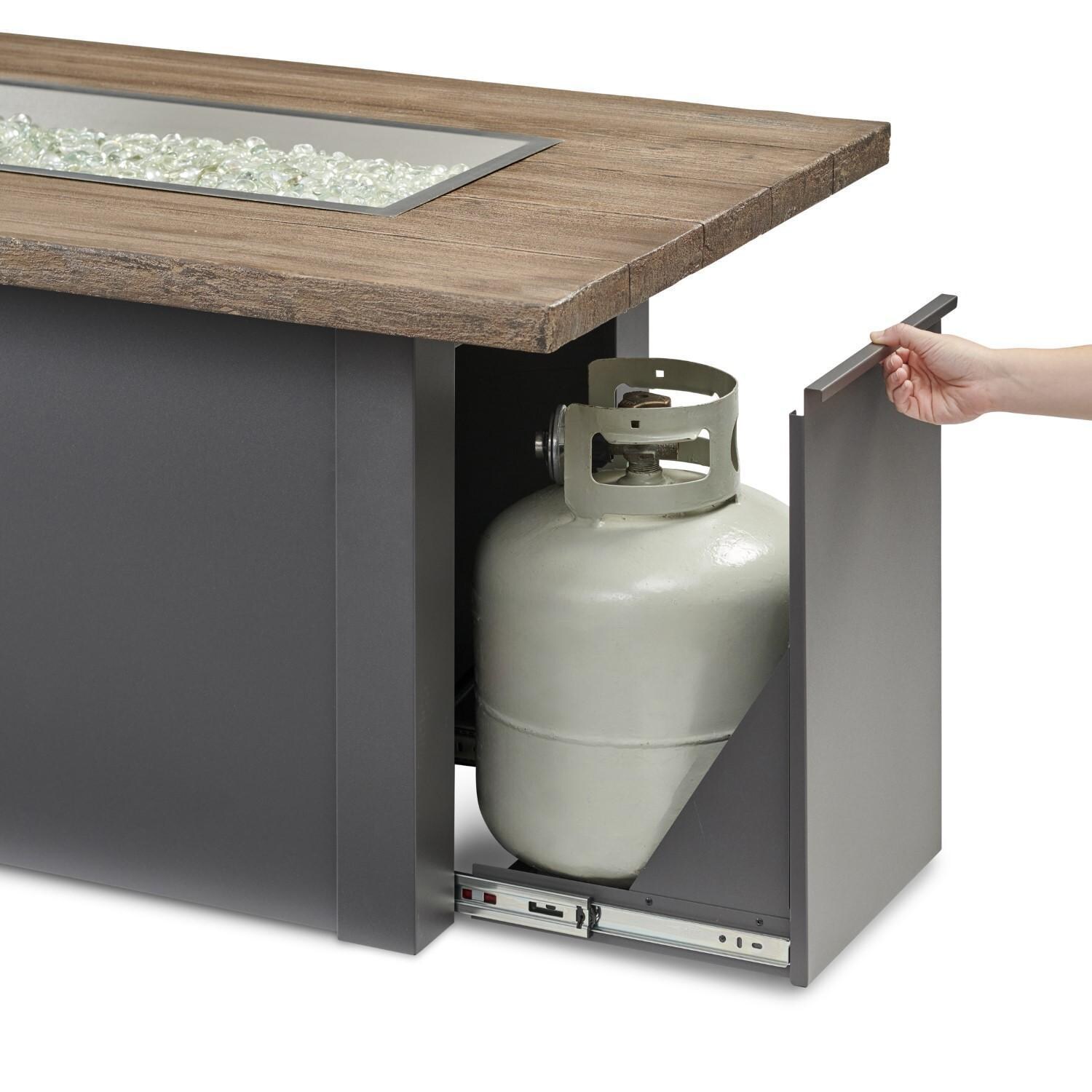 Havenwood 62 Inch Propane Fire Pit Table W/ Driftwood Top & Grey Base - Hand Reaching For Tank Drawer - Detail thumbnail