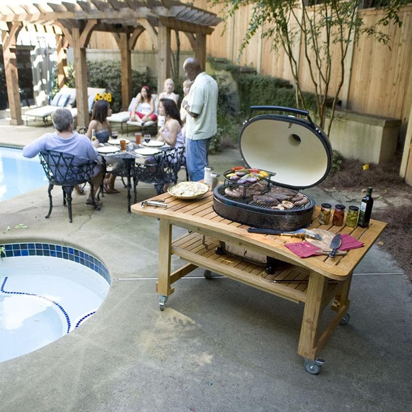 Primo PGCXLH Oval XL 400 Ceramic Kamado Grill On Curved Cypress Table With Stainless Steel Grates - By the Pool - Lifestyle thumbnail