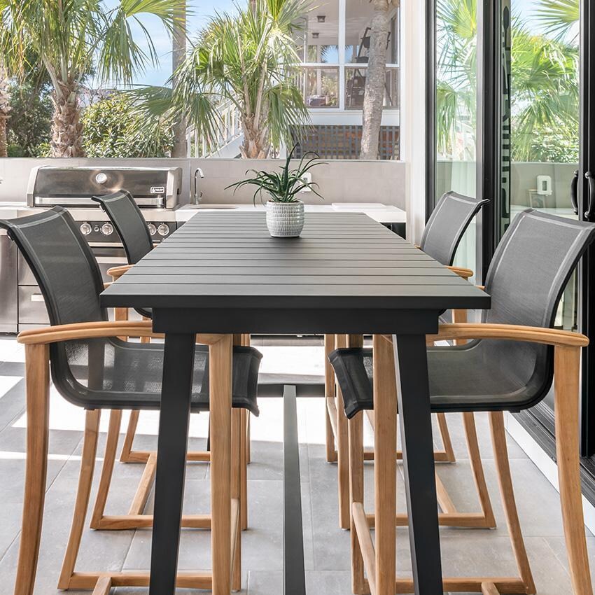 Teak + Table Capri Sling Bar Chair in Grey - On Patio Head of Table - Lifestyle thumbnail