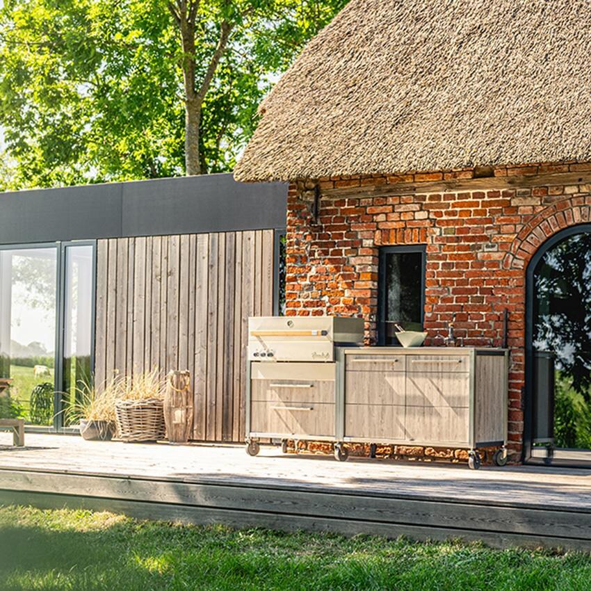 Burnout BBQ Modular Front-Lit Outdoor Kitchen Island w/ Flammkraft Model D Built-In Grill, Caso 4.4 Cu Ft. Refrigreator, Double Drawers, Propane Pullout, and Pullout Waste Bins- Not in Use On the Patio (Shown in Oak) - Lifestyle thumbnail