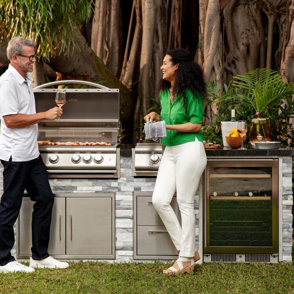 BBQGuys Signature 8 Ft Outdoor Kitchen Island w/ Blaze Premium LTE+ 32-Inch Natural Gas Grill, Premium LTE+ Power Burner, 24-Inch Beverage Cooler - Alaska Gray Stone w/ American Black Polished Granite - Gathered Around Island 2 - Lifestyle thumbnail