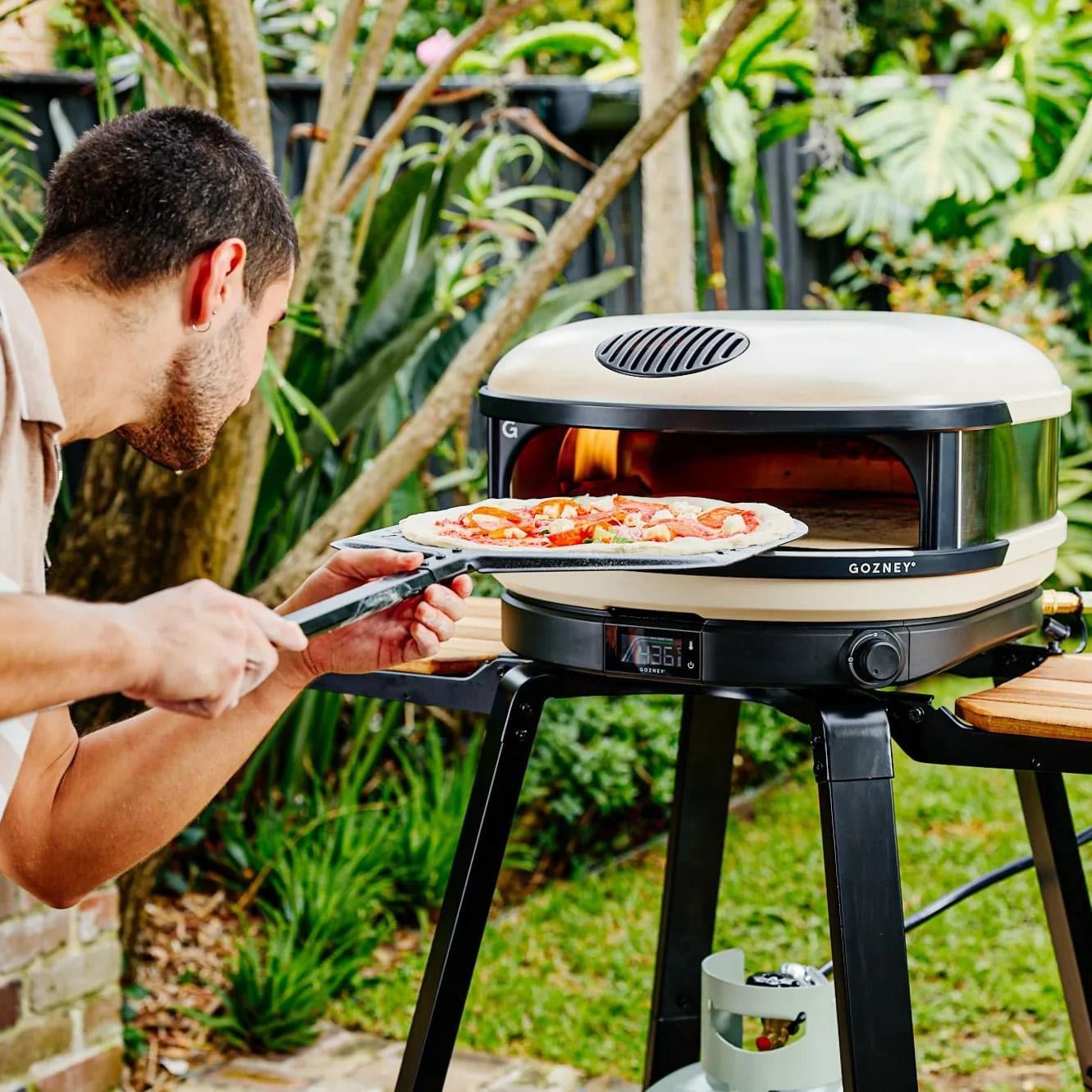 Gozney GAPBNUS1624 Bone Arc XL Propane Pizza Oven Essentials Bundle - Putting Pizza in Oven - Lifestyle thumbnail