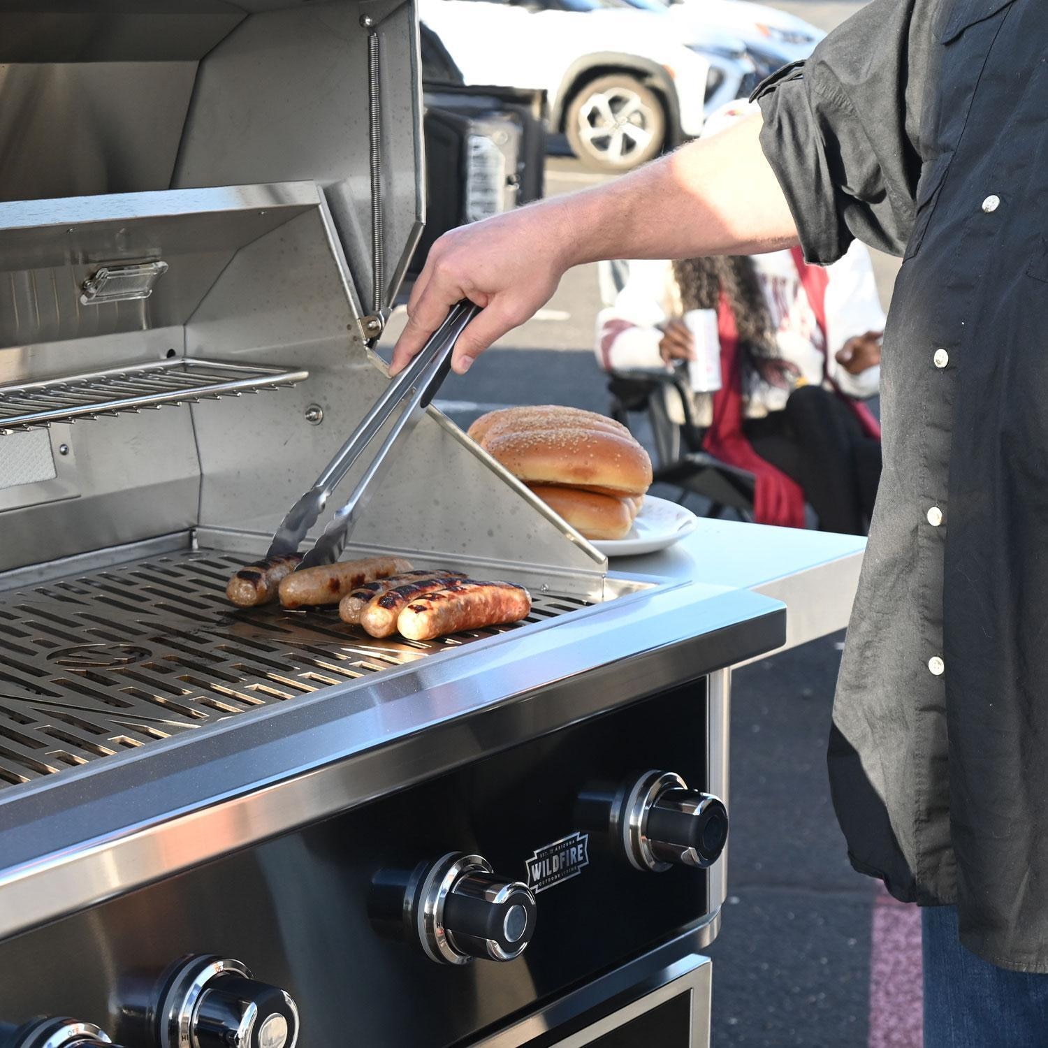 Wildfire Ranch Pro 42-in 304 SS Natural Gas Grill w/ Freestanding Cart - Flipping Hot Dogs - Lifestyle thumbnail