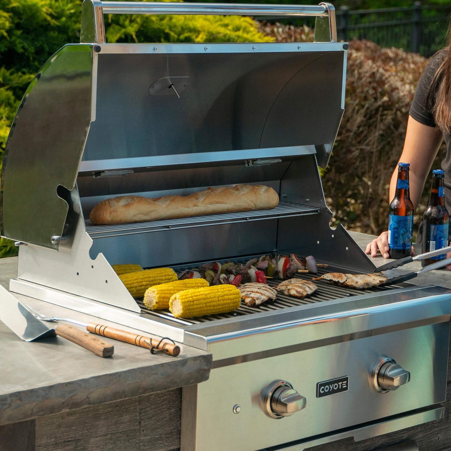 Coyote RTAC-G5-SG-C1C28LP Ready-To-Assemble 5 Ft Outdoor Kitchen Island With 28-Inch C-Series Propane Gas Grill - Stacked Stone/Stone Gray - Lifestyle View Grilling thumbnail