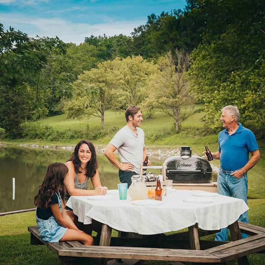 Primo PGCXLH Oval XL 400 Ceramic Kamado Grill On Curved Cypress Table With Stainless Steel Grates - By the Lake - Lifestyle thumbnail