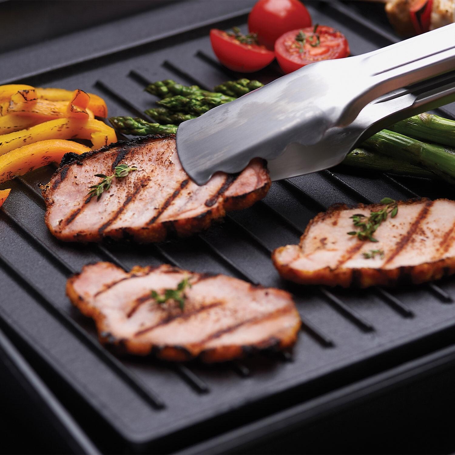 Broil King 11221 Exact Fit Cast Iron Griddle for Signet Series - Grabbing Ham W/ Tongs on Cast Iron Griddle - Lifestyle thumbnail