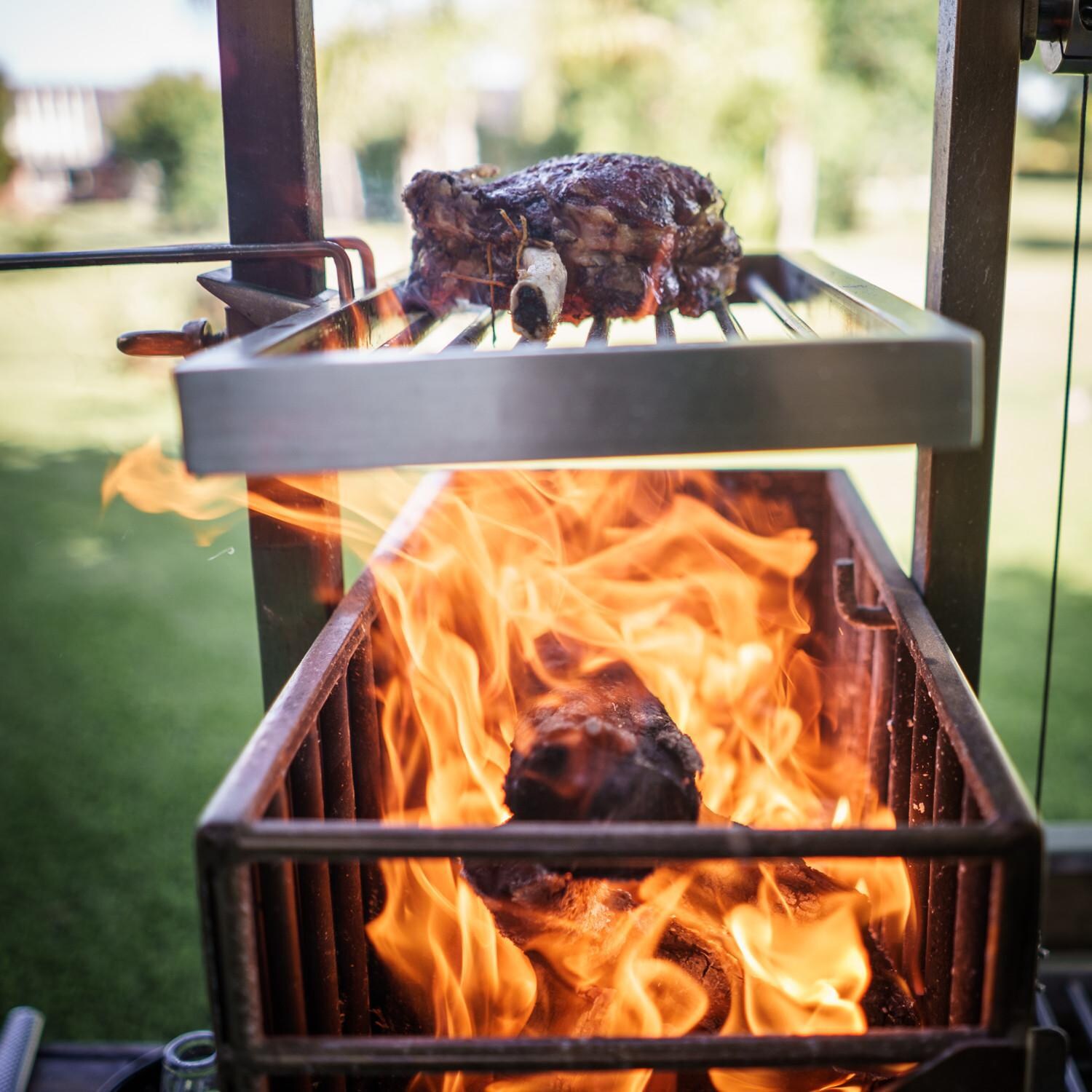Tagwood BBQ BBQ03SSF Fully Assembled All Stainless Steel Argentine Santa Maria Wood Fire & Charcoal Grill - Searing Steak on Secondary Grate Above Firebox