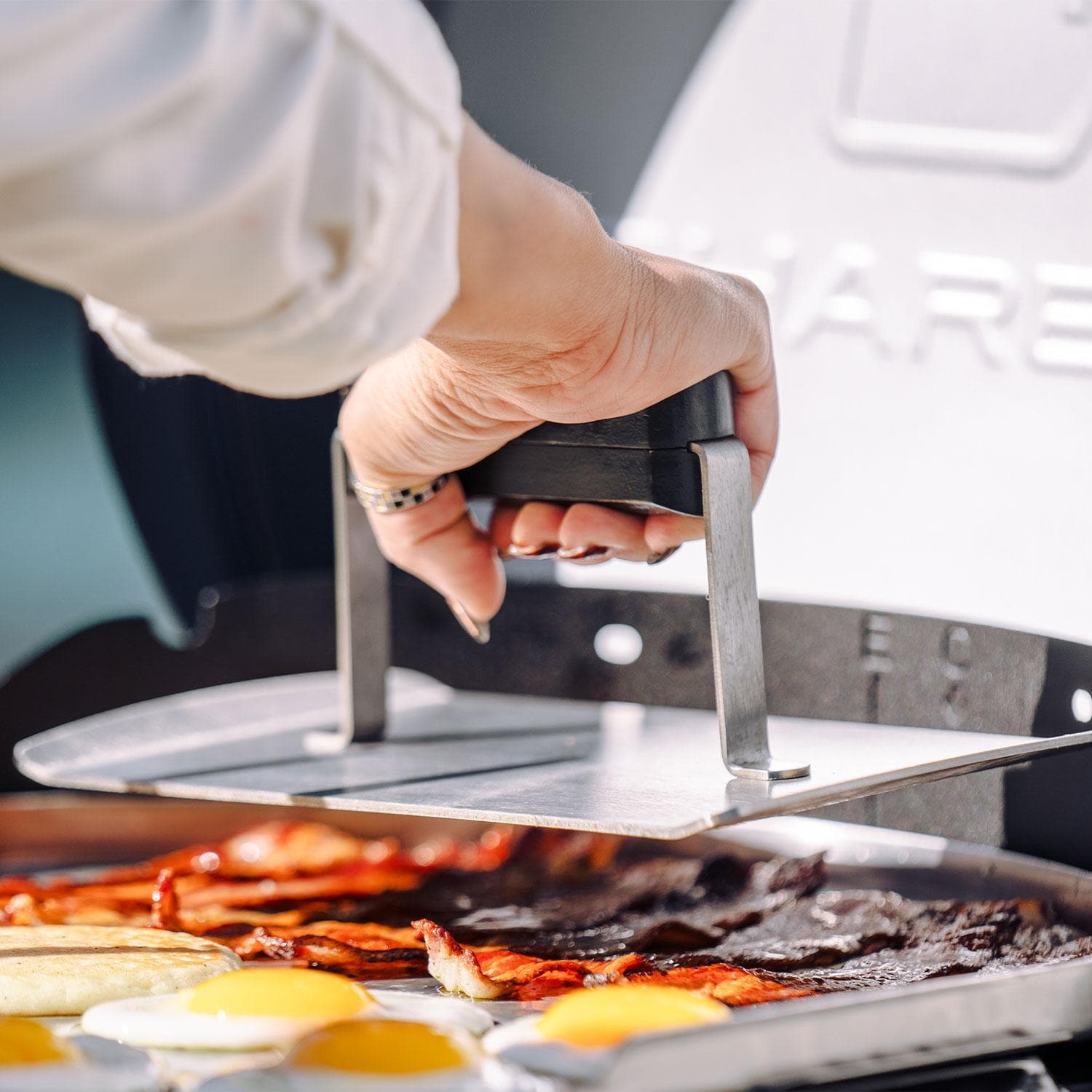 Charbroil 25302145 Bistro Pro 240 Electric + Freestanding Griddle - Black - Pressing Down Bacon - Lifestyle thumbnail