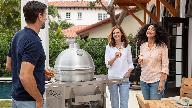 Man and two women in front of the Blaze Kamado Grill on grill cart