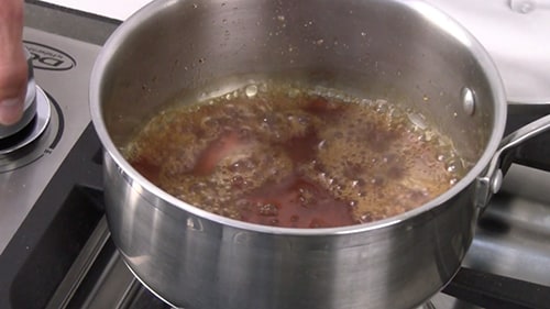 Caramel sauce cooking on the stove after adding water and whiskey