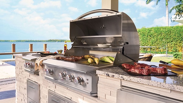 grilling steak and corn on the Blaze Professional LUX gas grill built into an outdoor kitchen island