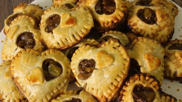 close up of golden brown heart-shaped apple hand pies piled on a plate