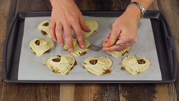 assembling heart-shaped apple hand pies on a cookie sheet