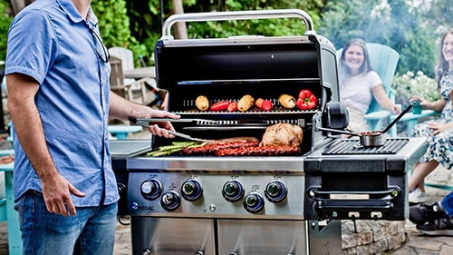 Person grilling food and utilizing the side burner