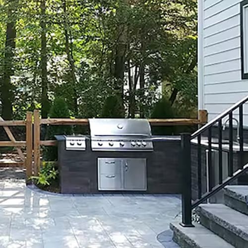Dark stone-clad cabinets and counter with a stainless steel grill, drawers, and doors