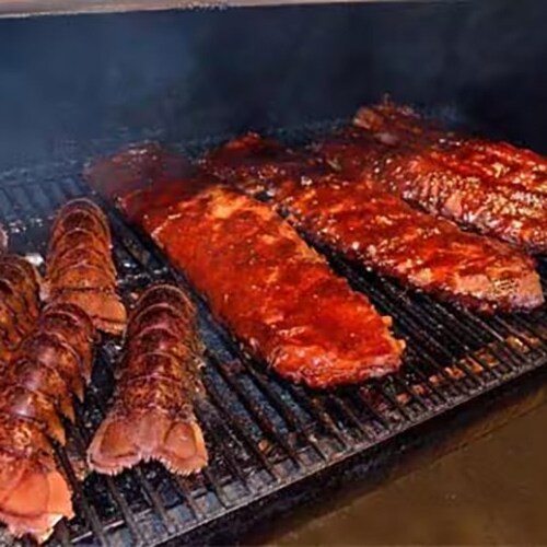 Lobster and bbq sauce covered ribs being smoked on a pellet grill