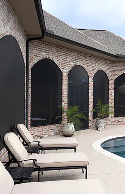 Chaise lounges set up next to a pool along the wall of a house