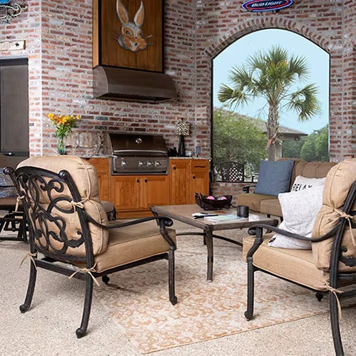 Outdoor kitchen and living space with wooden cabinets, a stainless steel grill, and a seating set