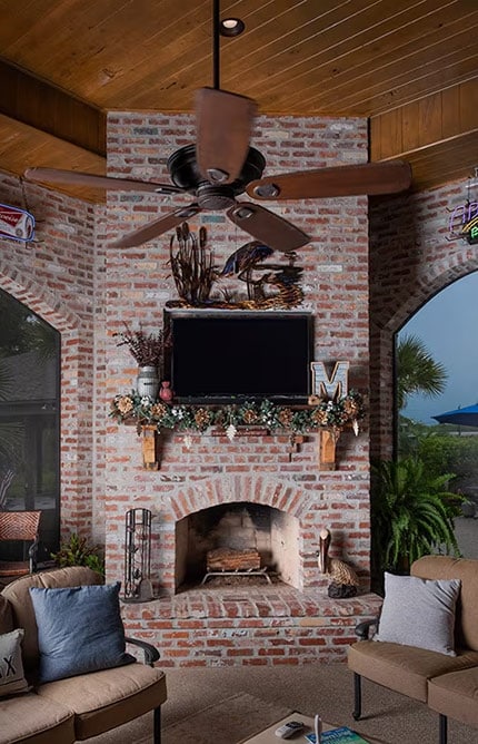 TV hanging above a brick fireplace, in front of a seating set