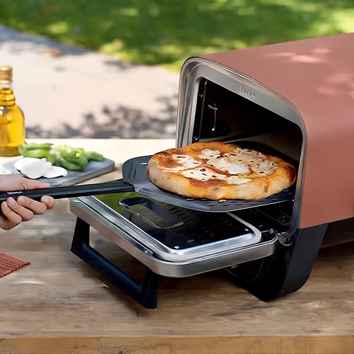 Pizza being launched into Ninja Woodfire Electric Pizza Oven