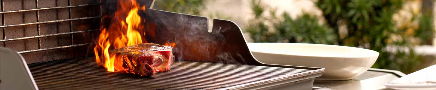 Steak searing on a grill with the lid open.