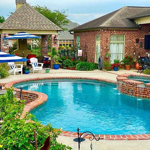 Beautiful brick lined pool, with an outdoor patio and kitchen nearby