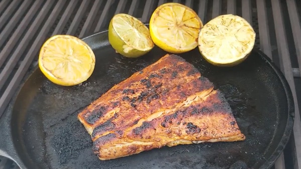 Salmon fillet on cast iron skillet with charred lemons and limes
