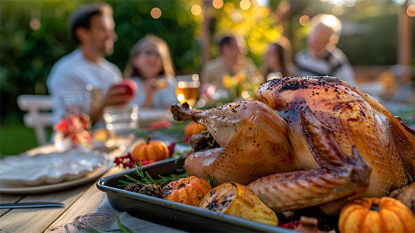 Cooked turkey on a table with white linencloth with people in background