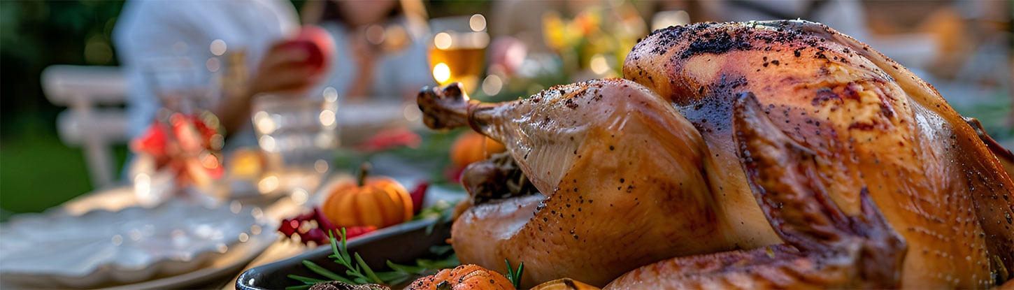 Cooked turkey on a table with white linencloth with people in background