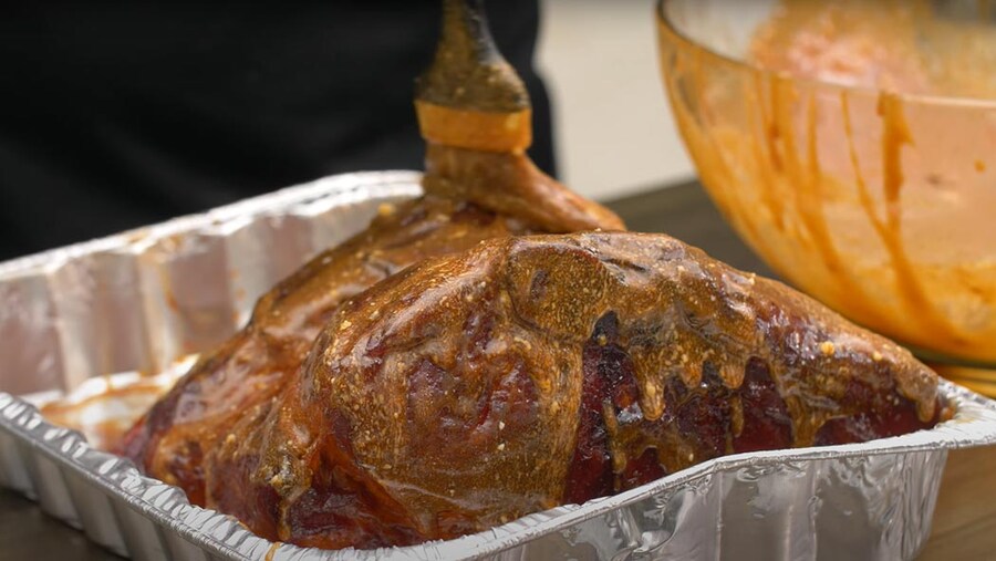 BBQ butt being slathered in sauce