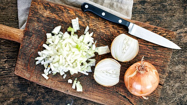 Whole and chopped onions on a chopping board