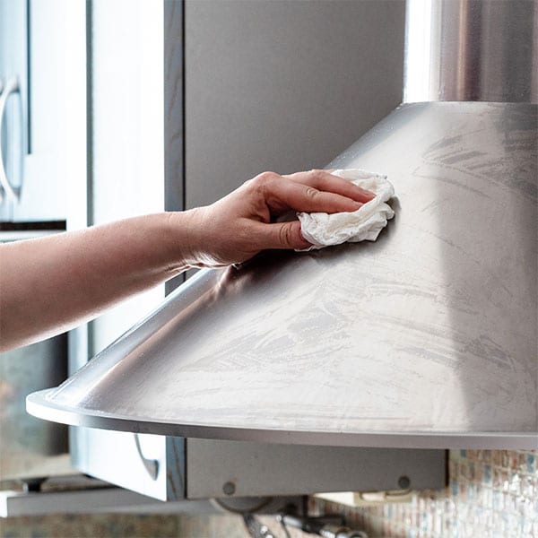 hand cleaning a stainless steel fixture with a rag