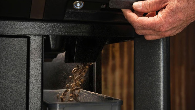 Opening the pellet release door to pour pellets into storage container