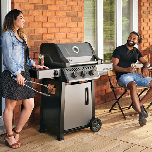 people standing near a freestanding gas grill with lid closed