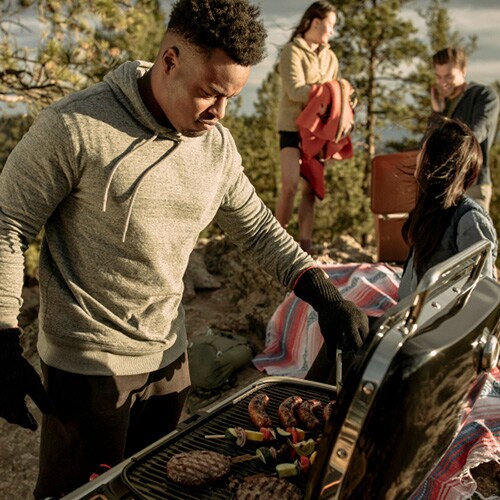Man cooking on portable gas grill at a campsite
