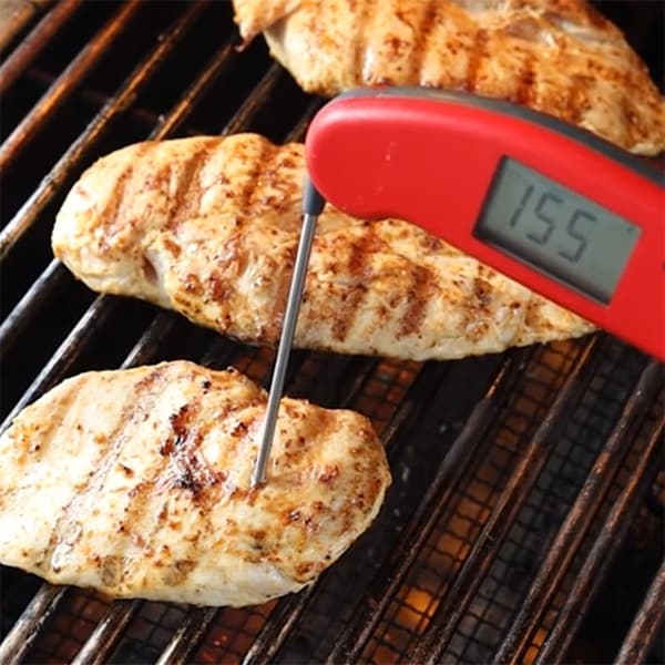 chicken breasts on a grill with thermometer inserted showing internal temperature of 165 F