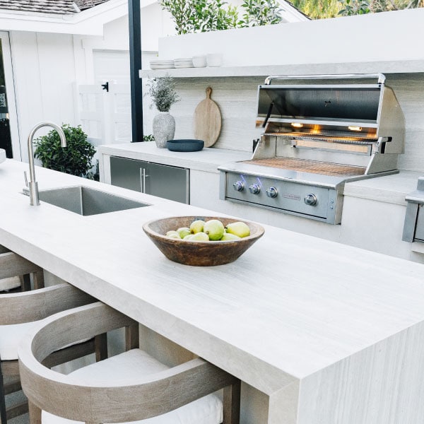 Outdoor kitchen with grill, refrigerator next to outdoor bar